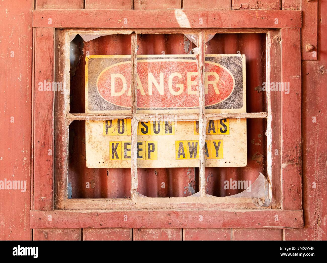Ancienne fenêtre rouge vintage avec verre brisé et un vieux panneau d'avertissement. Banque D'Images
