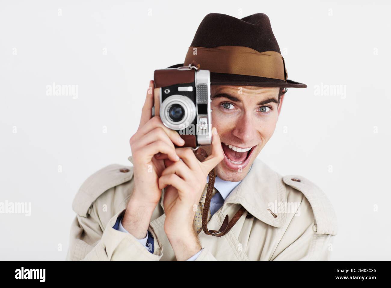 HES a pris la bonne photo. Journaliste prenant une photo avec un appareil photo rétro sur fond blanc avec une expression drôle. Banque D'Images