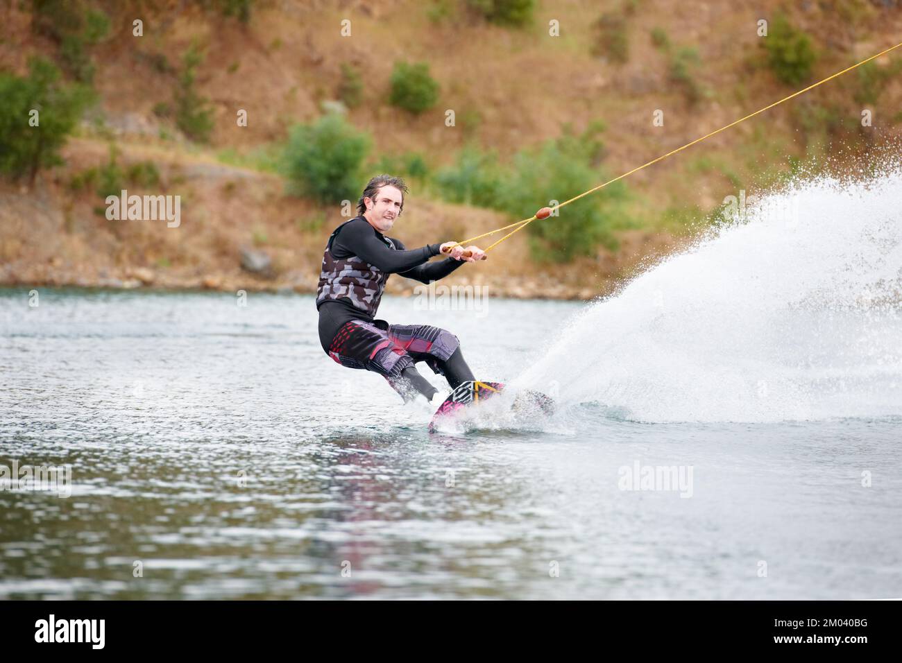 Avoir une explosion. Un jeune homme plein d'énergie qui fait du wakeboard sur le lac. Banque D'Images