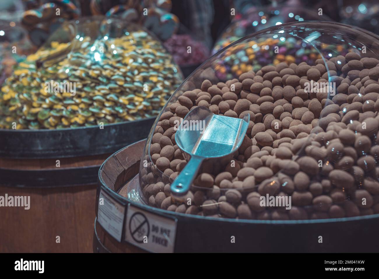 Une multitude de bonbons ronds au chocolat dans un distributeur en plastique avec une cuillère ou une pelle pour les sortir. Scène de la boutique de bonbons. Banque D'Images