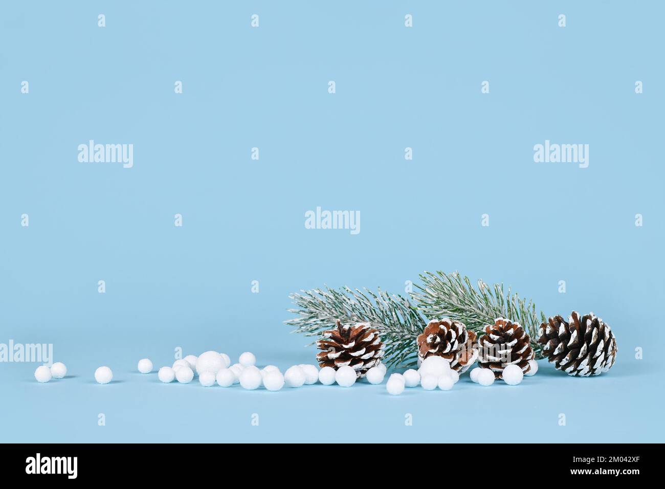 Composition de décoration d'hiver avec boules de neige, cônes de sapin et branches sur fond bleu avec espace de copie Banque D'Images