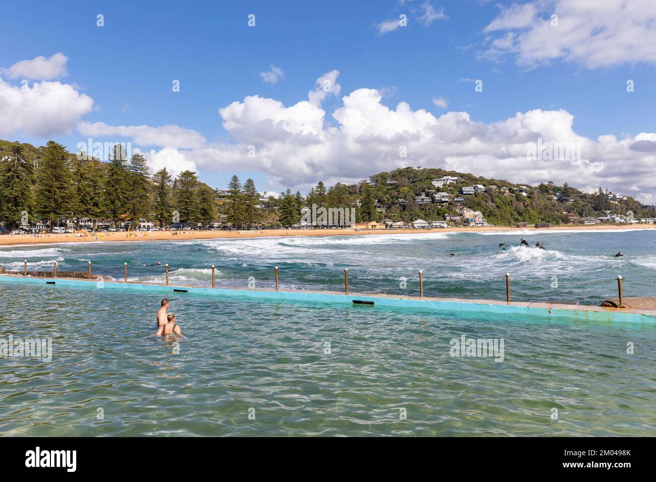 Palm Beach Sydney été 2022, les gens se trouvaient dans la piscine de roche de plage d'océan avec des sables de Palm Beach au loin, NSW, Australie Banque D'Images