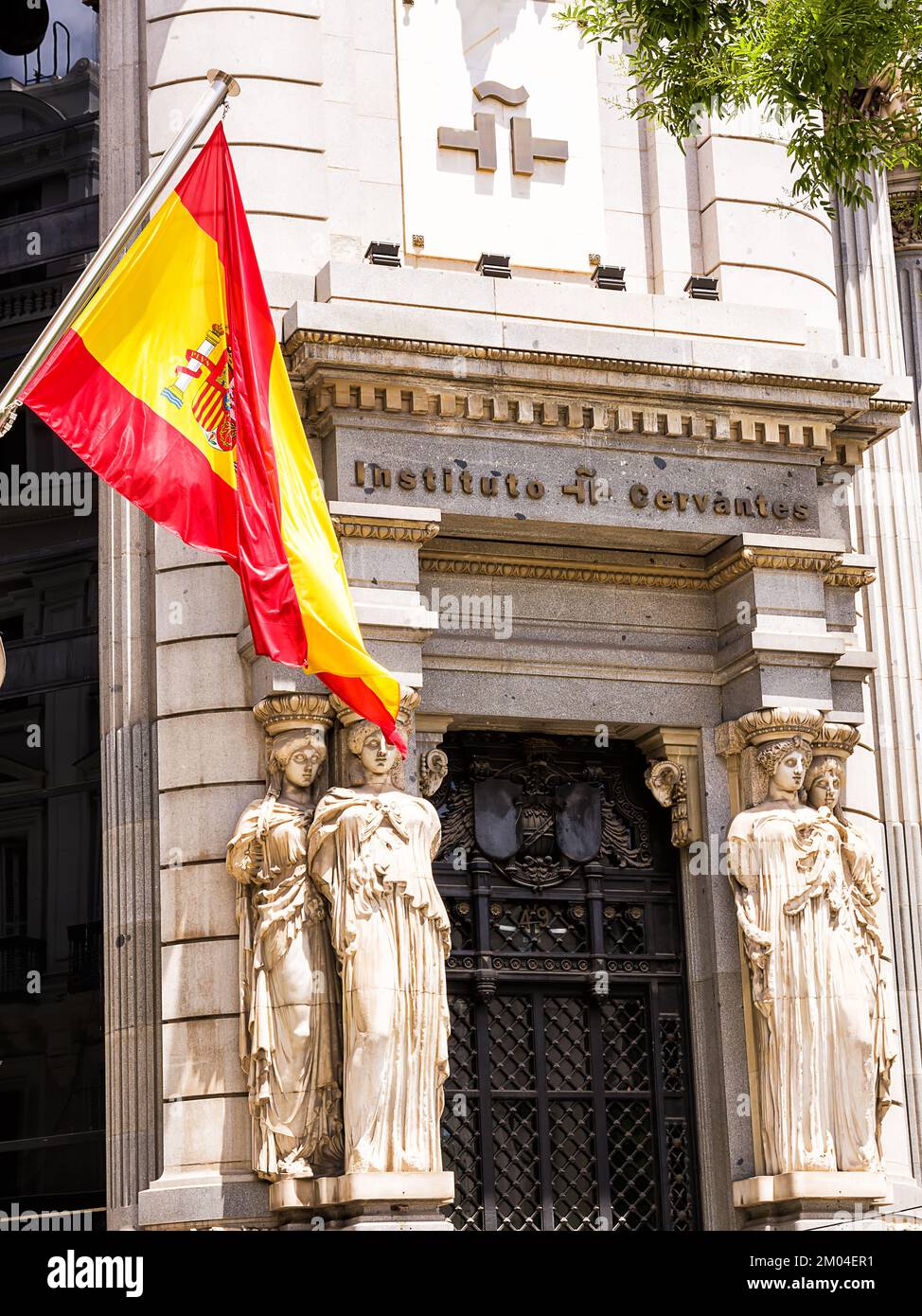 Madrid, Espagne - 20 juin 2022: Drapeau espagnol au premier plan et entrée du siège de Madrid de l'Institut Cervantes, un instituto that di Banque D'Images