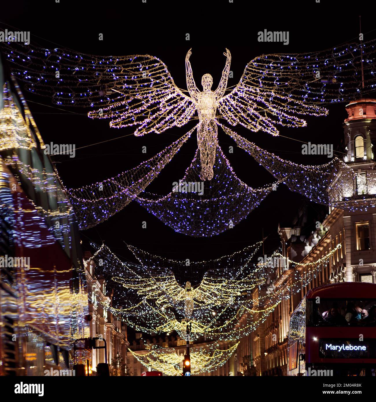 L'esprit de Noël s'affiche sur Regent Street avec les lumières réfléchis sur le côté d'un bus qui passe. Londres. Banque D'Images