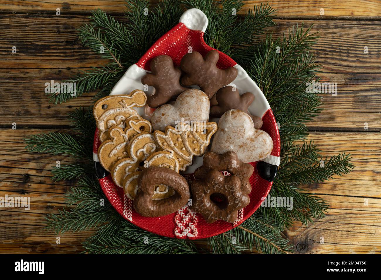 Biscuits de Noël en pain d'épice sur une assiette en forme de Père Noël et des branches d'arbre. Noël saison des fêtes composition d'hiver sur fond de bois. Banque D'Images
