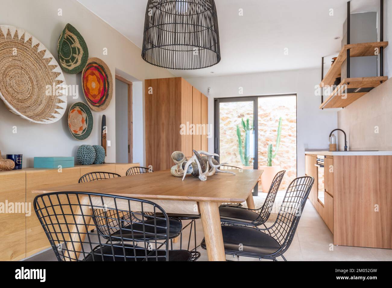 Cuisine moderne et lumineuse avec une table à manger avec des trophées byzantins au centre, des chaises et un lustre en tiges de métal, décorativ Banque D'Images