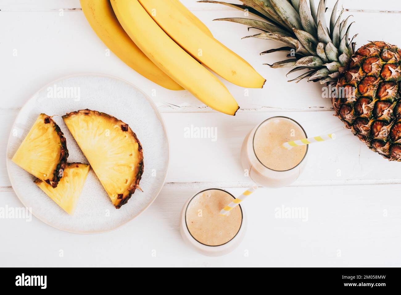 Smoothie à la banane et à l'ananas sur une table en bois blanc avec ingrédients. Detox concept de régime, boisson de vitamine d'été. Vue de dessus, plan d'agencement. Banque D'Images