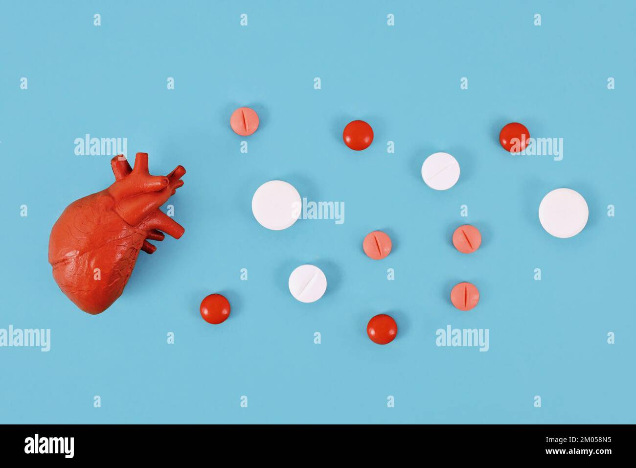 Modèle d'organe de coeur à côté des pilules sur fond bleu. Concept pour les maladies cardiaques Banque D'Images
