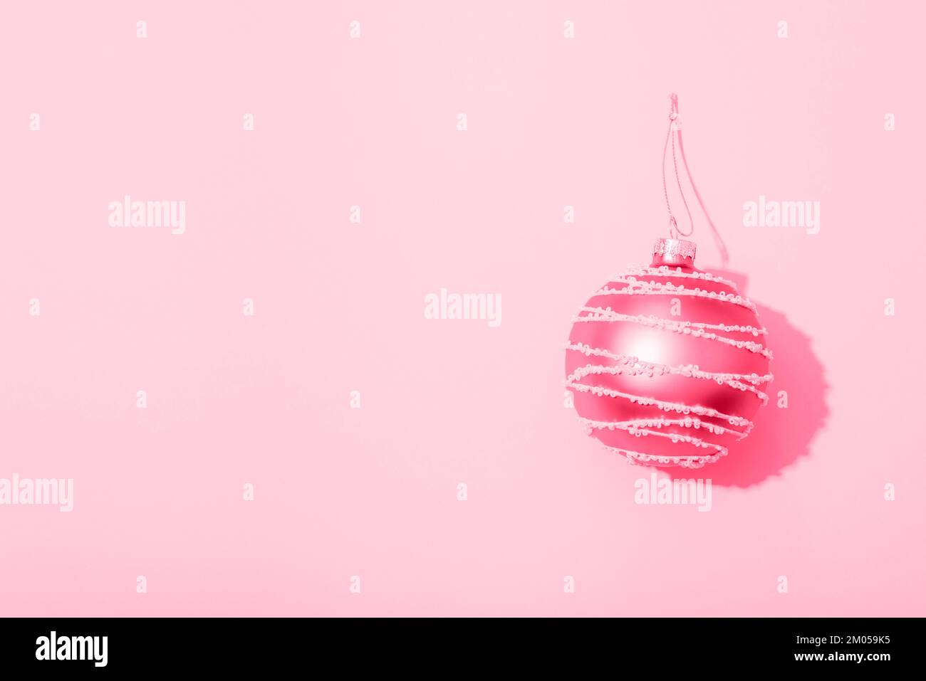 Boule de Noël sur fond rose avec une ombre nette. Vue de dessus, plan d'agencement, espace de copie. Banque D'Images