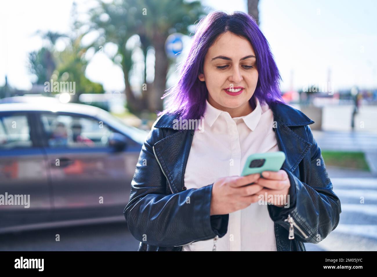 Jeune femme belle et grande taille souriant en toute confiance en utilisant  un smartphone dans la rue Photo Stock - Alamy