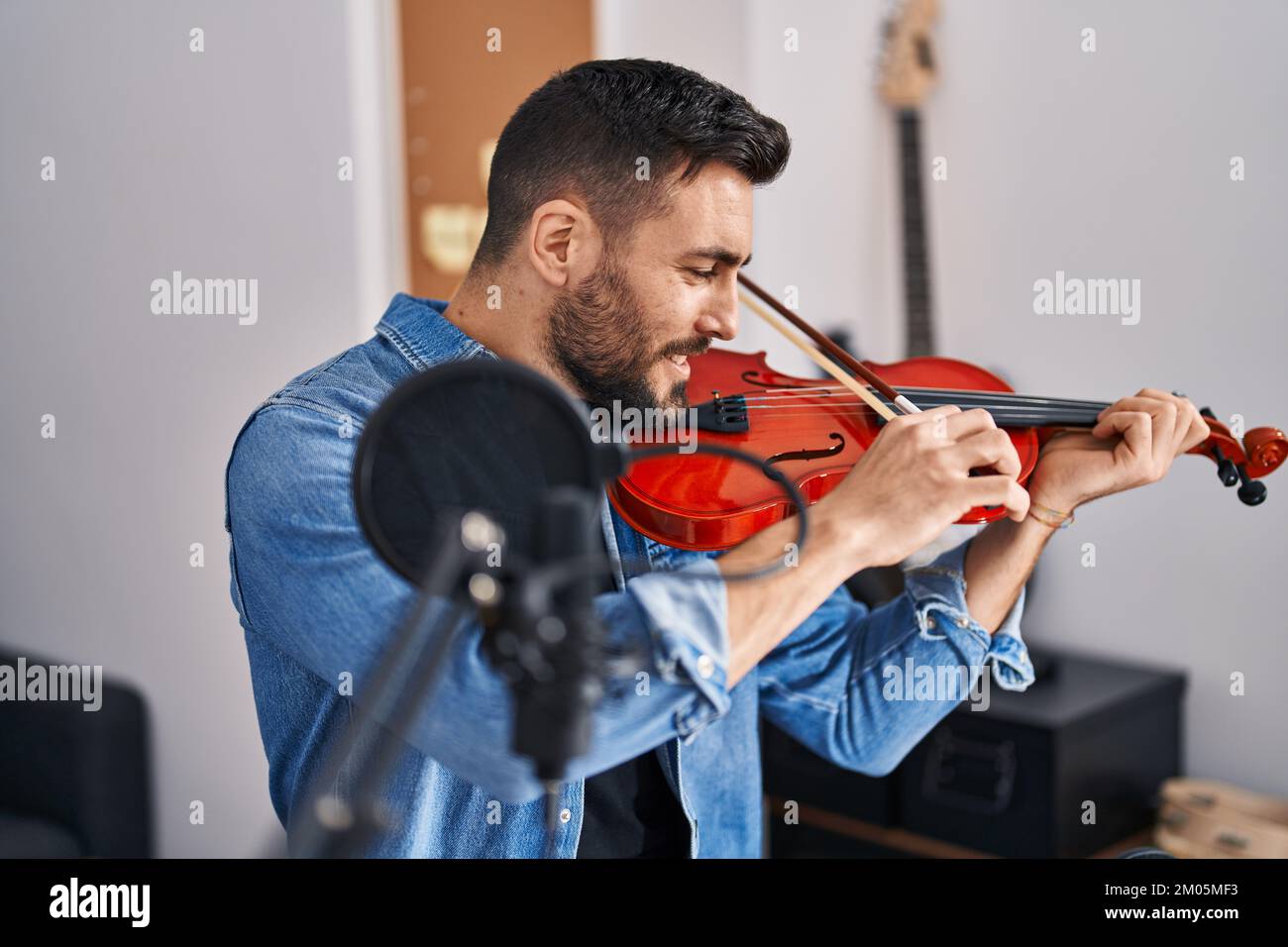 Jeune homme hispanique musicien jouant du violon dans un studio de musique Banque D'Images