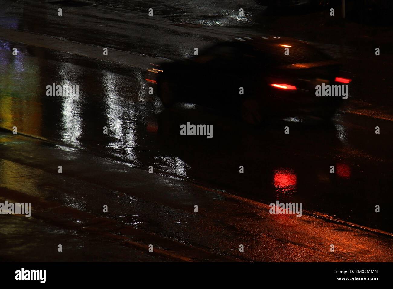 Une voiture floue qui s'emballe avec des sentiers de queue lors d'une nuit de pluie. Banque D'Images