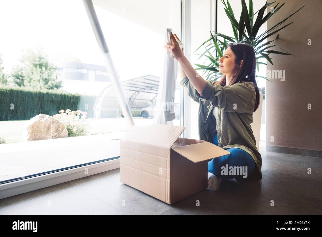 Femme caucasienne prenant les vêtements hors de la boîte, les hommes de courrier viennent de lui apporter Banque D'Images