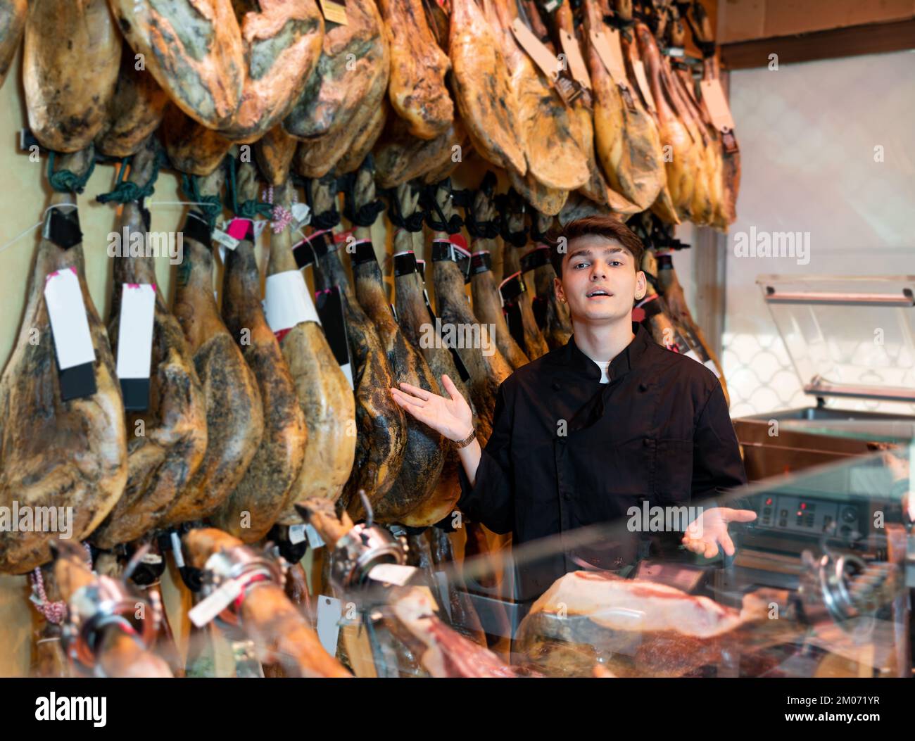 Jeune gars vendeur en blouson noir vendant jamon espagnol sec-cured dans la  boutique de boucher Photo Stock - Alamy