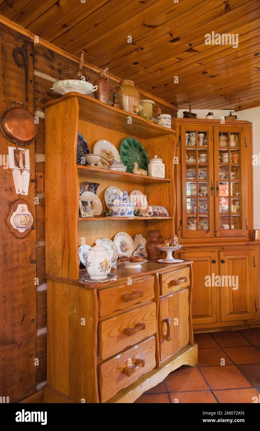 Buffets antiques avec collection assortie de porcelaine et curiosités dans la cuisine à l'intérieur de la vieille maison en rondins de style cottage reconstruit des années 1800. Banque D'Images