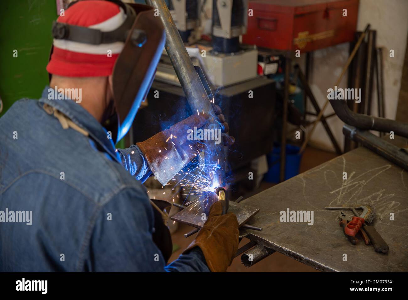 Soudeur en usine soudant une pièce métallique, portant un écran facial et des gants de protection Banque D'Images