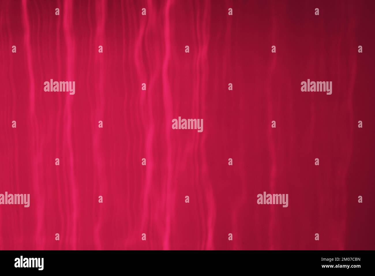 Viva Magenta couleur de l'année 2023. Le reflet des rayons du soleil sur le mur. Réflexions solaires inhabituelles. Banque D'Images