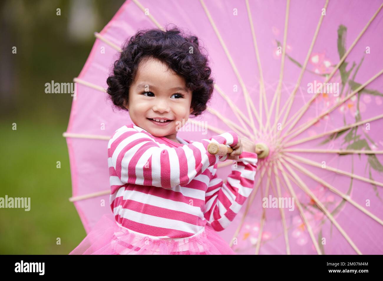 TRS fantaisie. une adorable petite fille jouant avec un parapluie rose à l'extérieur. Banque D'Images