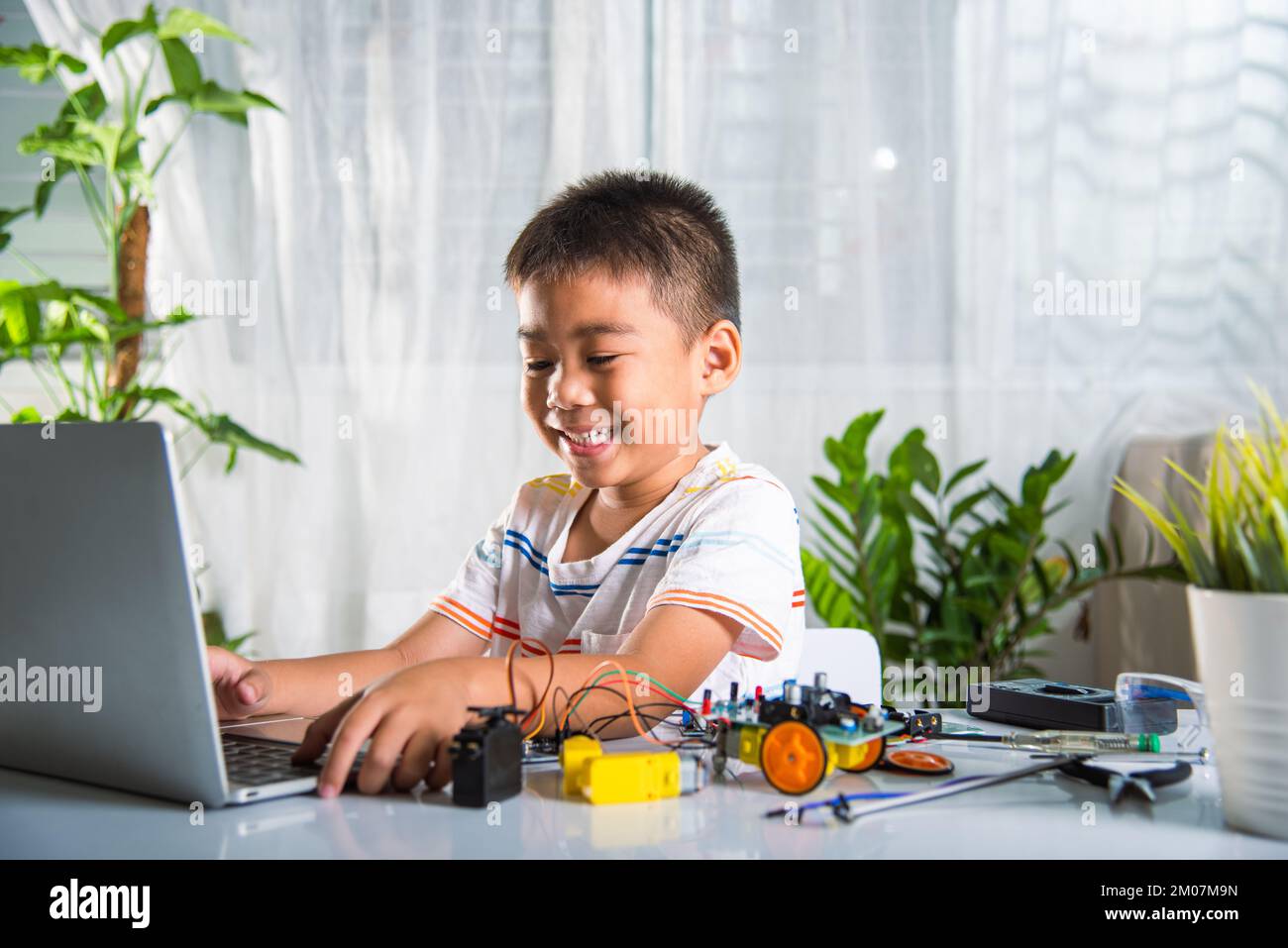 Un enfant asiatique apprend le codage et la programmation avec un ordinateur portable pour la voiture robot Arduino Banque D'Images
