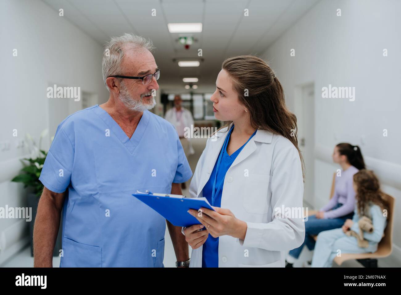 Un médecin plus âgé donne des conseils à son jeune collègue, discutant dans le couloir de l'hôpital. Concept de soins de santé. Banque D'Images