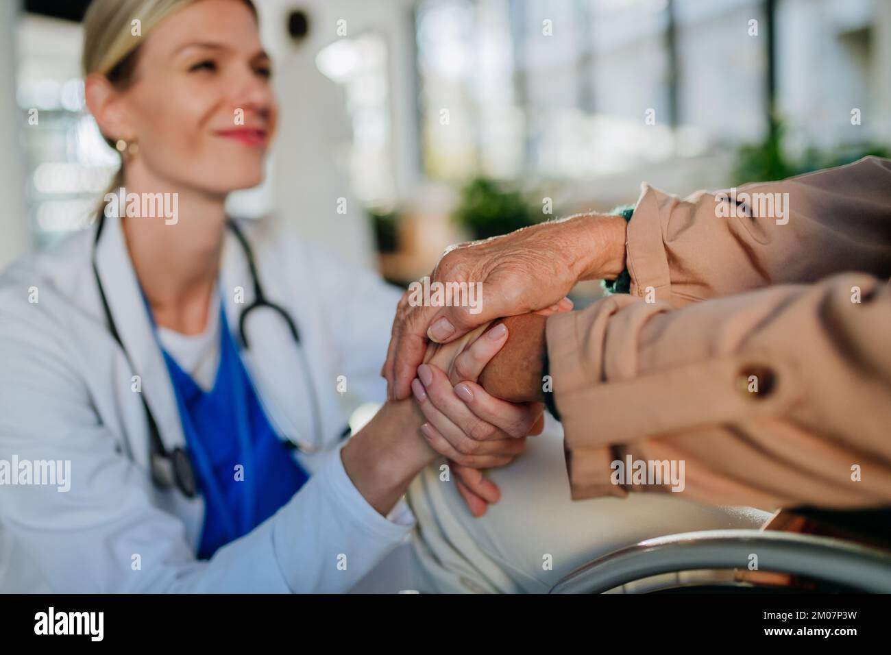 Gros plan de la jeune femme médecin tenant les mains de la patiente, la consolant. Banque D'Images