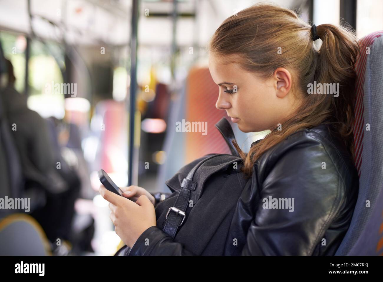 Je suis en route. Une adolescente envoyant un texte de son siège sur le bus. Banque D'Images