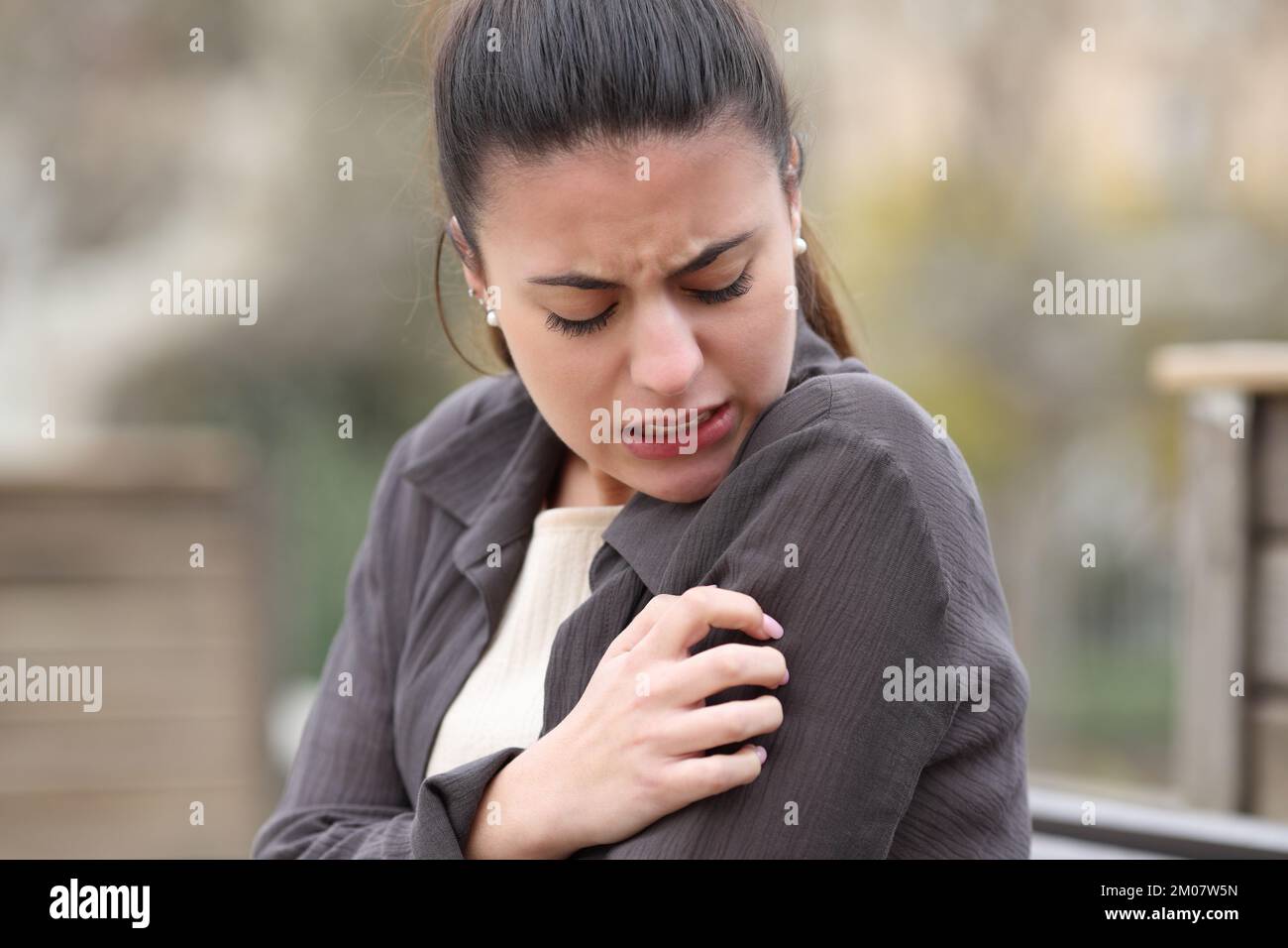 Femme stressée en train de rayer le bras qui démange dans un parc Banque D'Images