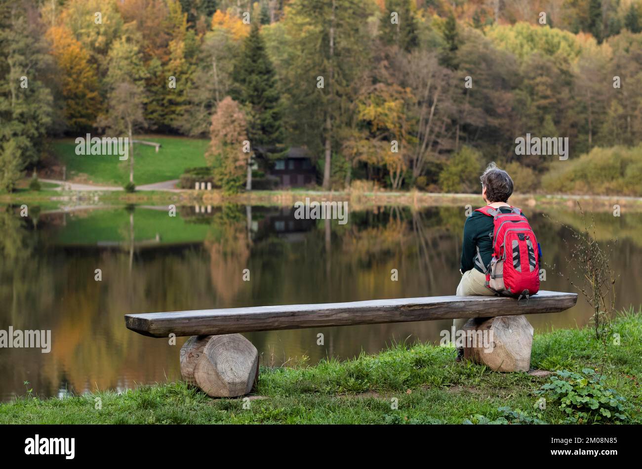 Femme plus âgée avec sac à dos, Best Ager, assis seul sur un banc en bois, Ebnisee, Kaisersbach, automne, forêt souabe, Bade-Wurtemberg, Allemagne, Europe Banque D'Images