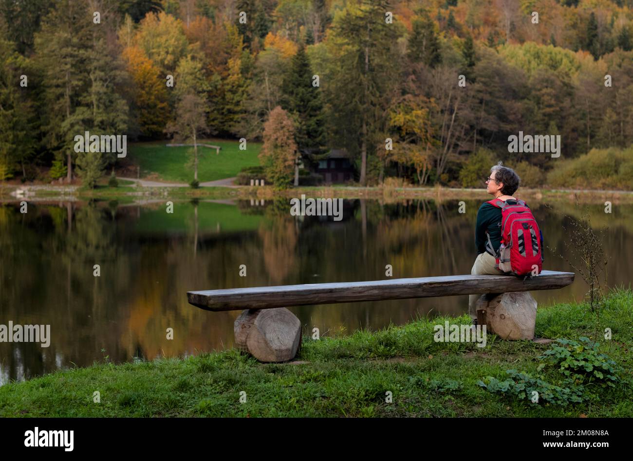 Femme plus âgée avec sac à dos, Best Ager, assis seul sur un banc en bois, Ebnisee, Kaisersbach, automne, forêt souabe, Bade-Wurtemberg, Allemagne, Europe Banque D'Images