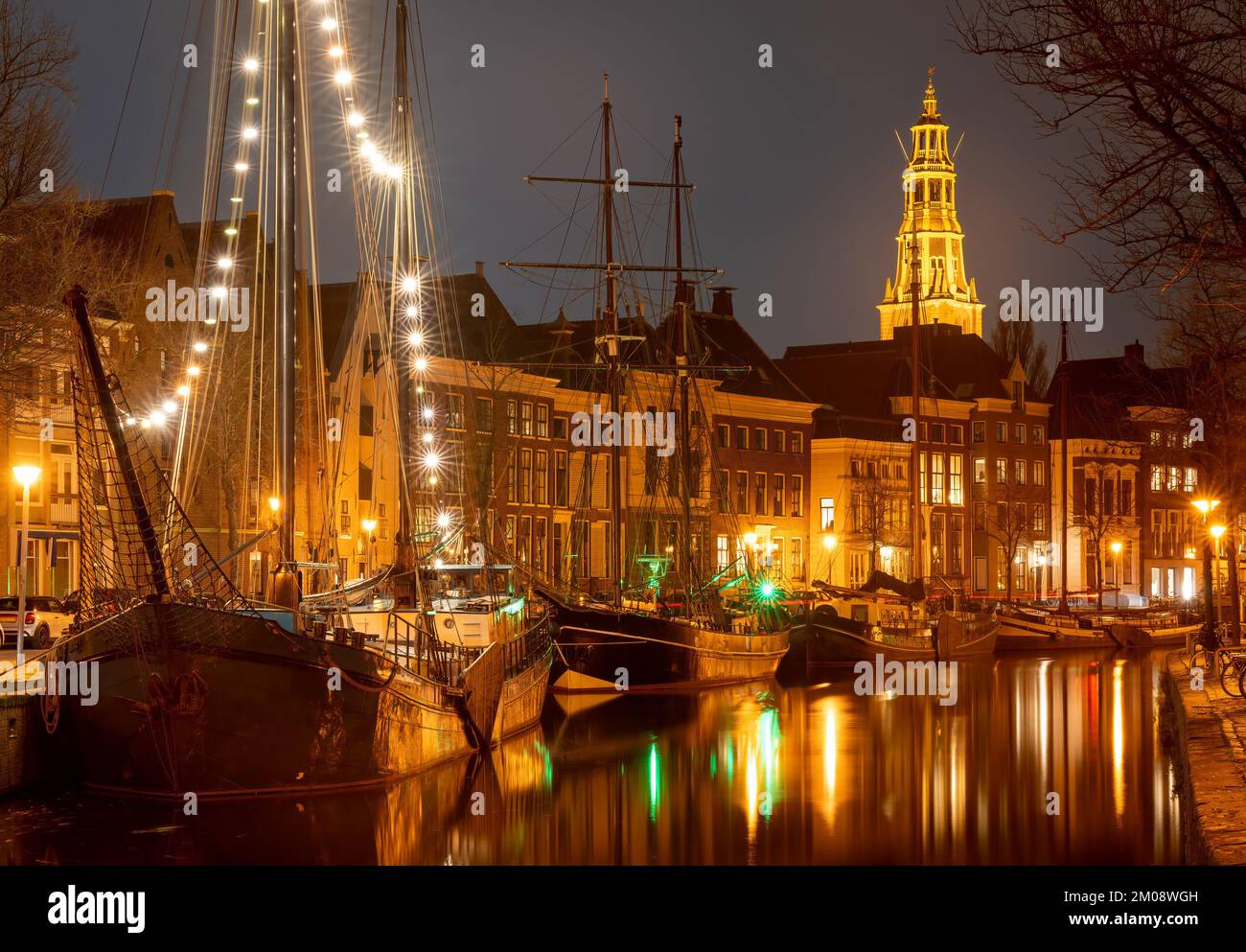 Paysage urbain de Groningen la nuit, vue sur les navires historiques, le canal et la tour de l'église Banque D'Images