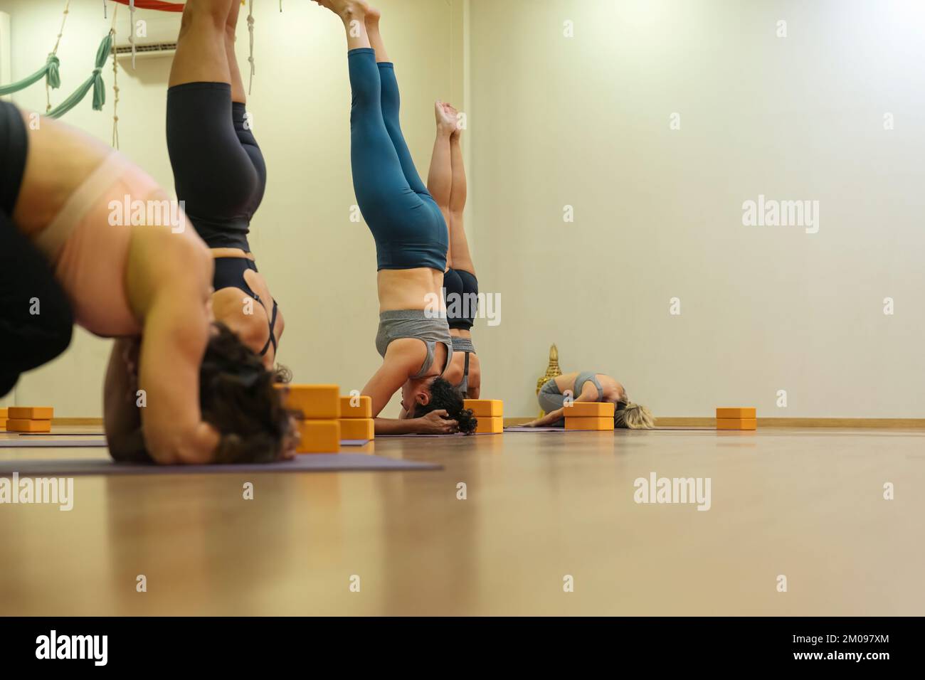 Groupe de femmes en cours de yoga faisant le Shirshasana Une pose Banque D'Images