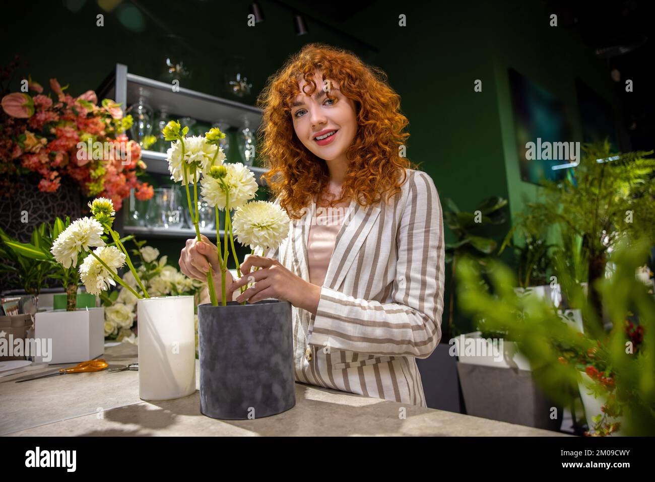 Fleuriste au gingembre aux cheveux bouclés tenant des pots de fleurs Banque D'Images