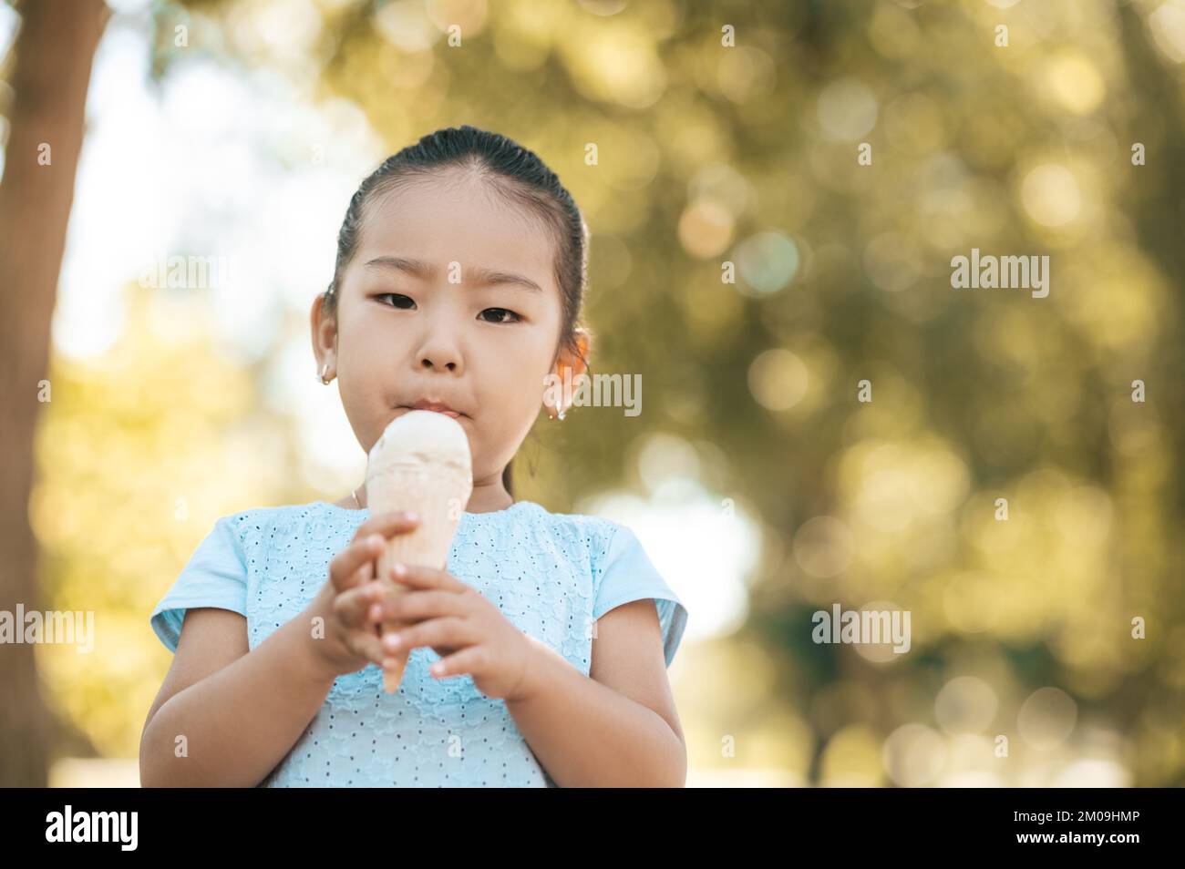 Petite fille mignonne qui mange de la glace et qui a l'air content Banque D'Images