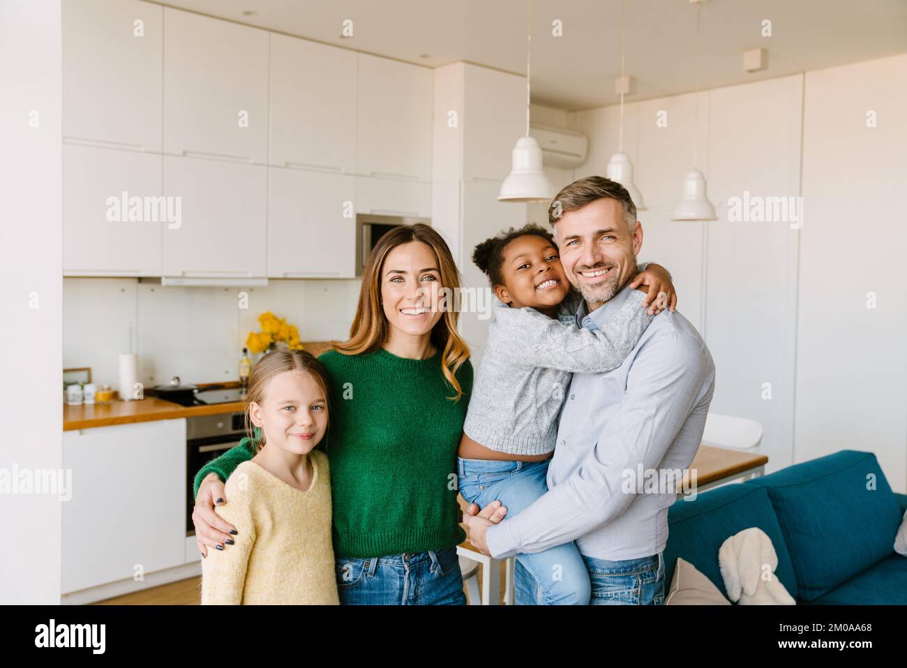 Bonne famille dans la cuisine confortable à la maison. Père, mère et deux filles. Concept d'adoption Banque D'Images