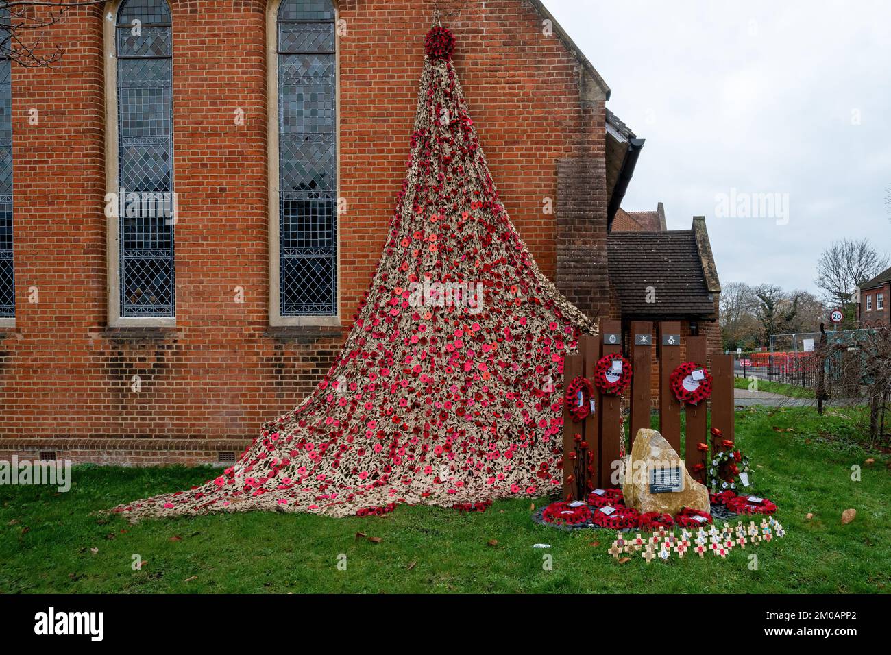 Cascade de coquelicots avec des croix et des couronnes en souvenir à côté de la pierre du mémorial de guerre à l'extérieur de l'église à Farnborough, Hampshire, Angleterre, Royaume-Uni, en 2022 Banque D'Images