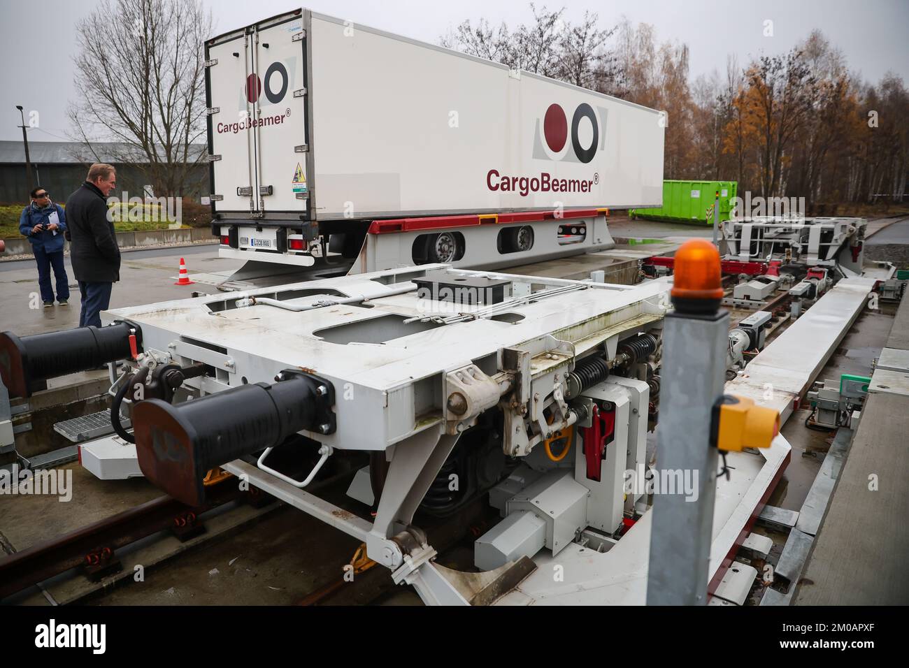 05 décembre 2022, Saxe, Leipzig: Burkhard Jung (SPD), Lord Mayor of Leipzig, regarde comme une semi-remorque avec une nouvelle technologie de chargement est chargée sur un wagon dans une station de fret. La société CargoBeamer, basée à Leipzig, souhaite l'utiliser pour rendre le transport de marchandises en Europe plus efficace et plus respectueux de l'environnement. Dans le nouveau terminal, les remorques de camions peuvent être déplacées latéralement sur le wagon à l'aide d'un bac de chargement. Cela permet de contourner le problème suivant : presque toutes les remorques ne peuvent pas être levées par grue, ce qui rend le chargement par rail coûteux et inutile. La maquette Banque D'Images