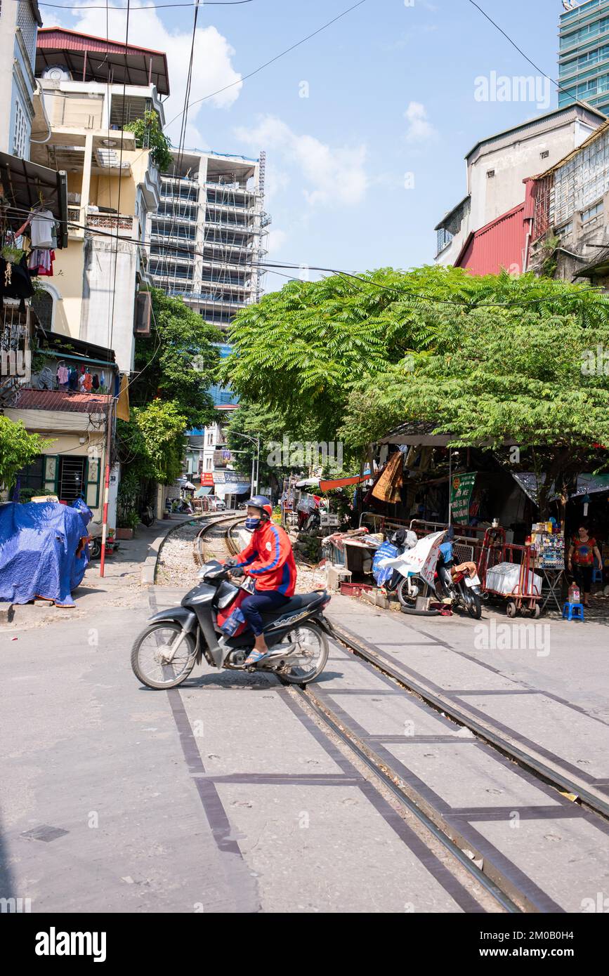 Hanoï, Vietnam - 16 septembre 2018: Un jeune homme en combinaison traverse la piste de train sur son scooter Banque D'Images