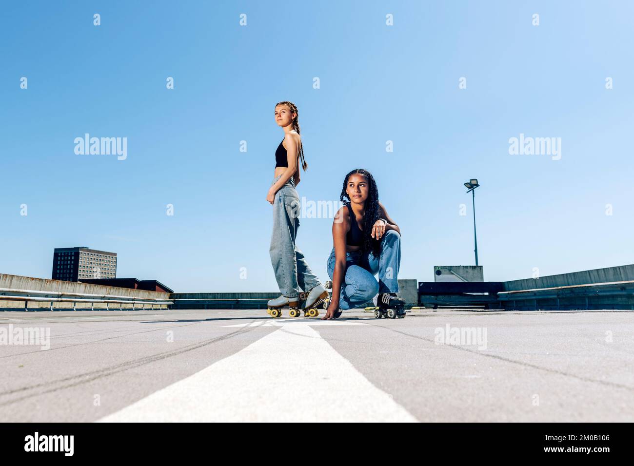 Deux filles patineuses à roulettes sur un parking extérieur au soleil. Banque D'Images