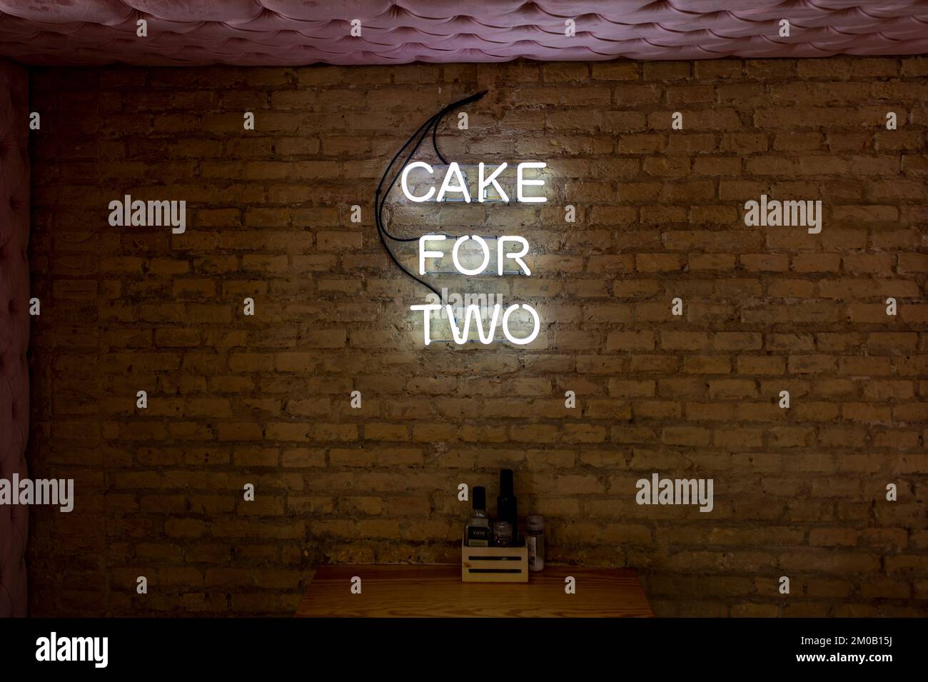 enseigne lumineuse au néon « gâteau pour deux » sur un mur à l'intérieur d'un café. Banque D'Images