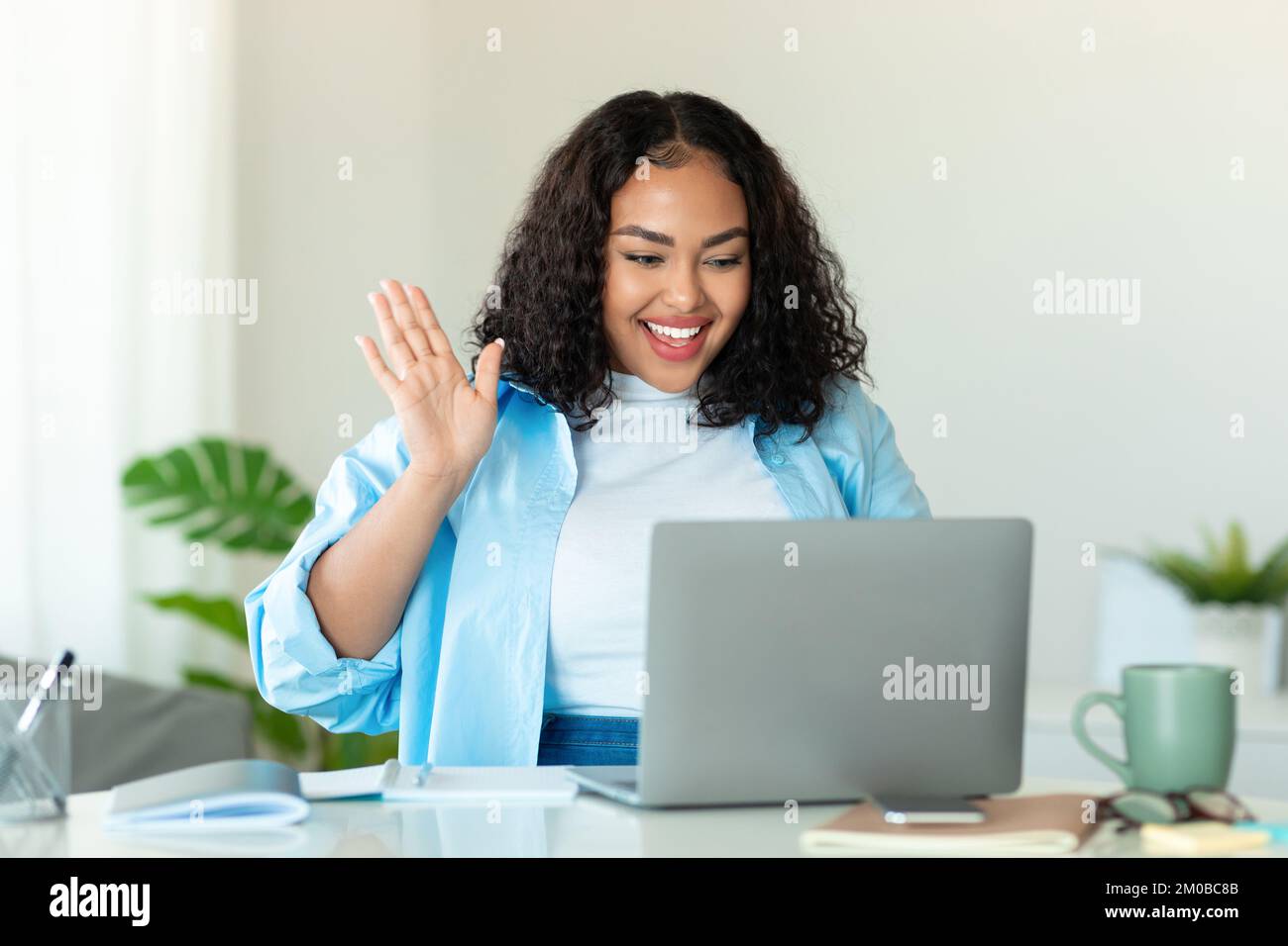 Concept de réunion en ligne. Bonne femme noire de corps positif utilisant un ordinateur portable pour la conférence virtuelle, ayant des appels vidéo à la maison Banque D'Images