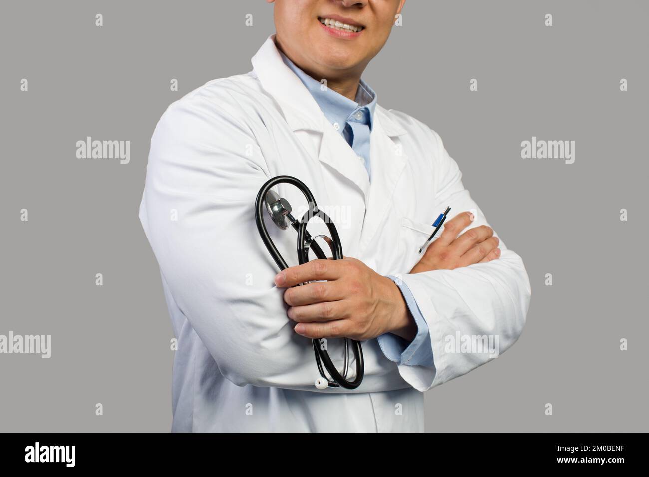 Un homme chinois souriant et confiant, un adulte, un thérapeute en manteau blanc avec stéthoscope, isolé sur fond gris Banque D'Images