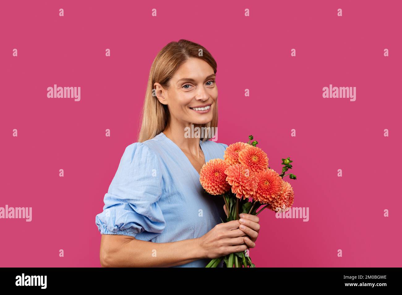 Portrait de l'adulte heureux blanc femelle en robe avec bouquet de fleurs regarde l'appareil photo Banque D'Images