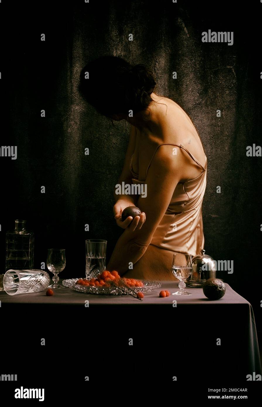 Femme offrant un fruit de la passion entre la vaisselle en cristal II Banque D'Images