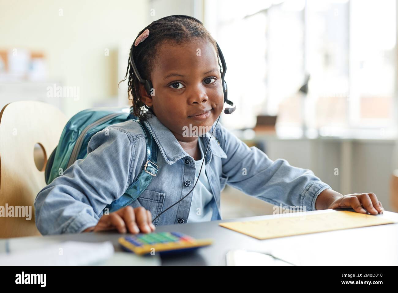 Portrait d'une petite fille noire mignonne jouant à la maison bureau travail avec la calculatrice et regardant l'appareil photo Banque D'Images