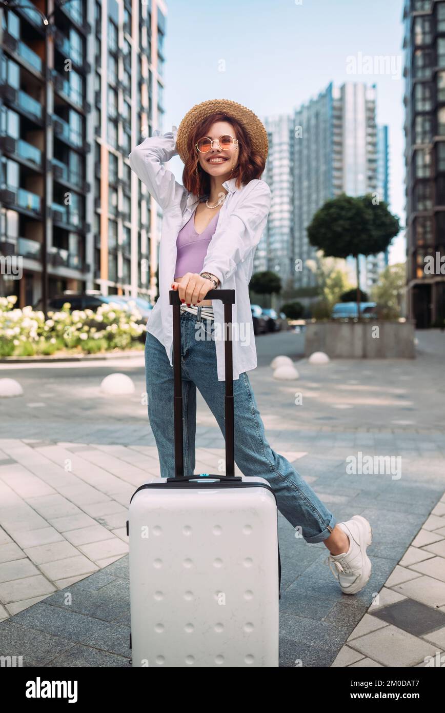 Femme élégante avec valise regardant l'appareil photo Photo Stock - Alamy