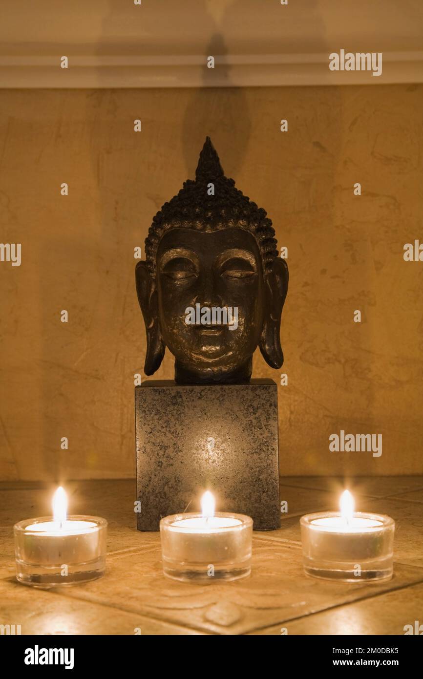 Statue de la tête de Bouddha illuminée par des bougies Photo Stock - Alamy