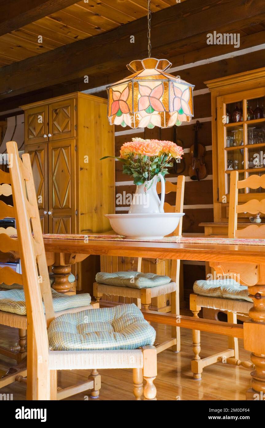 Chaises en bois de pin, table et meubles dans la salle à manger à l'intérieur de la maison en rondins de style cottage Canadiana. Banque D'Images