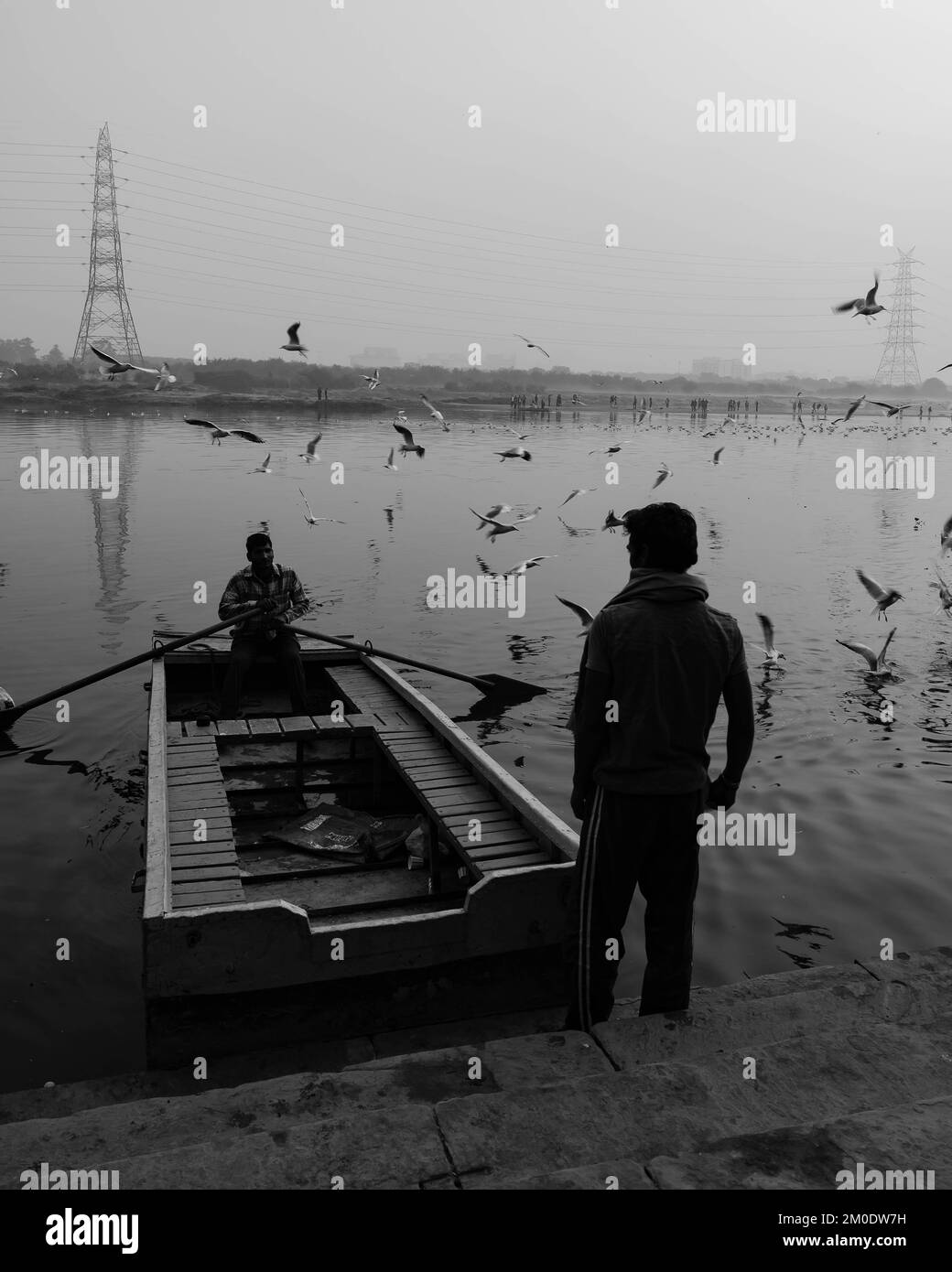 Une photo verticale en niveaux de gris de pêcheurs sur un bateau en bois sur la rivière Yamuna en Inde Banque D'Images