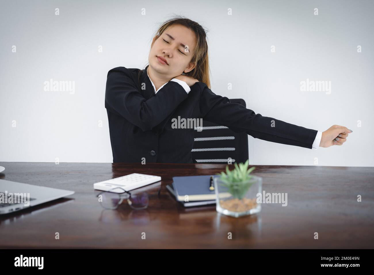 Femme d'affaires souffrant de douleurs à l'épaule sur le lieu de travail. Banque D'Images