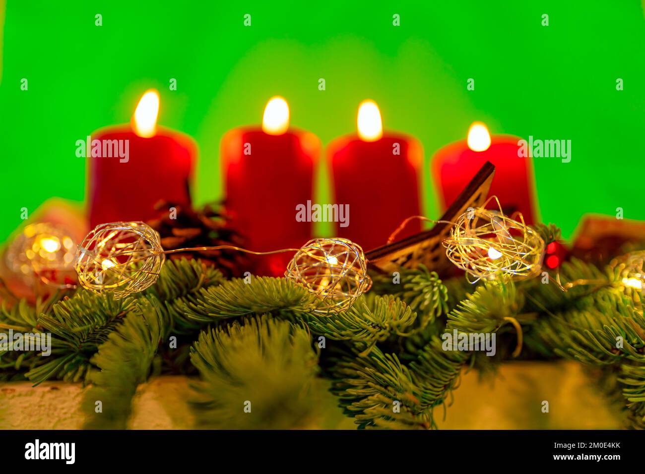 Bougies allumées pour X-Mas sur une couronne advents avec un fond vert neutre. Banque D'Images